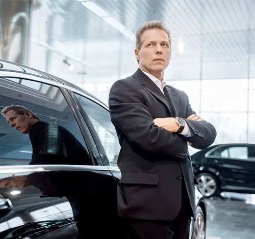 Chauffeur in a suit waiting beside his car